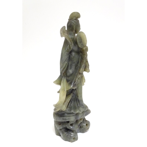 867 - An Oriental carved soapstone figure of a lady holding a fan, wearing flowing robes, on a carved base... 