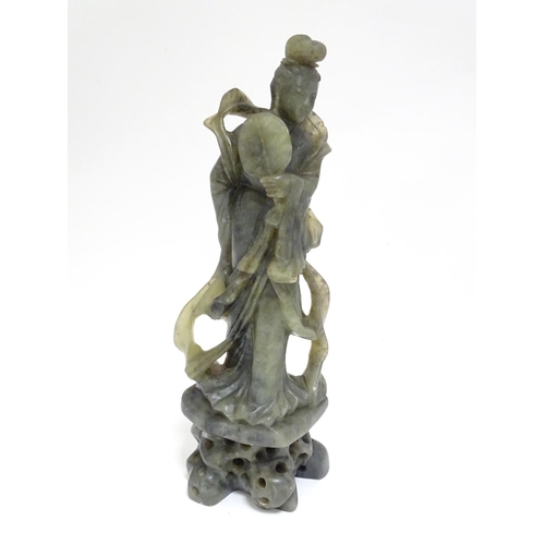 867 - An Oriental carved soapstone figure of a lady holding a fan, wearing flowing robes, on a carved base... 