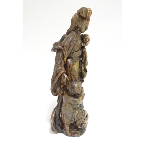 871 - A Chinese carved soapstone figural group modelled as Guanyin and a child, the goddess  holding a flo... 