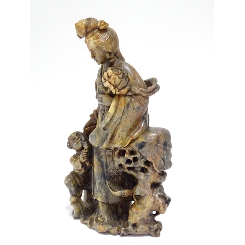 871 - A Chinese carved soapstone figural group modelled as Guanyin and a child, the goddess  holding a flo... 