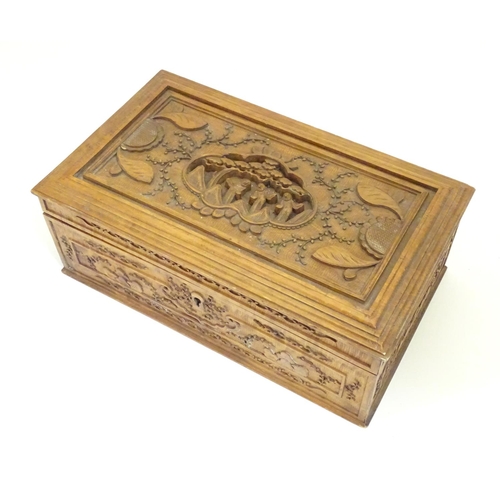 877 - A camphor wood box with carved floral and foliate detail, the lid with a carved vignette depicting a... 