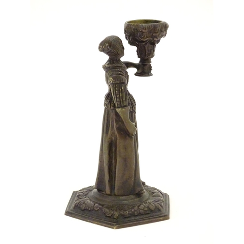 889 - A 19thC cast bronze figure of a woman holding a vase aloft on a hexagonal base with foliate decorati... 