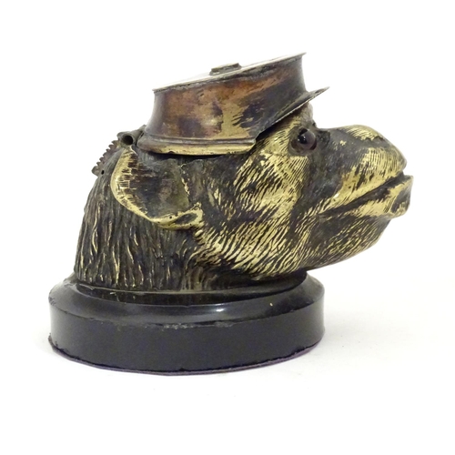 907 - A Victorian novelty brass desk inkwell formed as the head of a monkey with glass eyes wearing a hat.... 