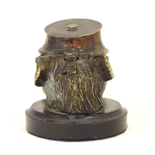 907 - A Victorian novelty brass desk inkwell formed as the head of a monkey with glass eyes wearing a hat.... 