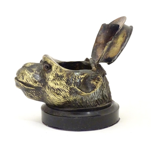 907 - A Victorian novelty brass desk inkwell formed as the head of a monkey with glass eyes wearing a hat.... 