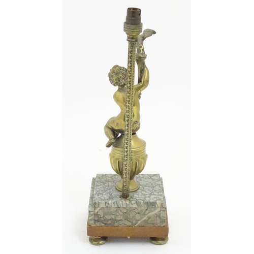 1215 - A 20thC table lamp decorated with cast figure of a putto holding aloft a bird, mounted upon a square... 