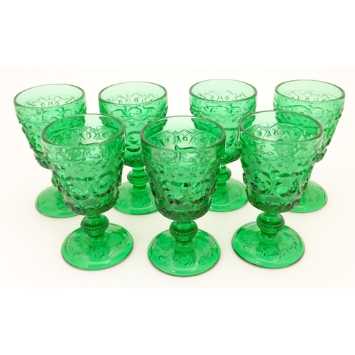 160 - A set of 7 vintage green glass  pedestal glasses with moulded decoration . Approx 4