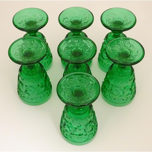 160 - A set of 7 vintage green glass  pedestal glasses with moulded decoration . Approx 4