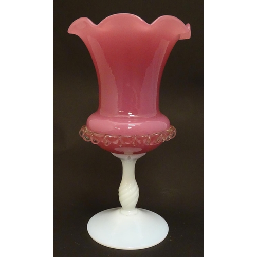 169 - A glass vase, the pink glass body with wavy rim and clear frilled decoration, raised over a milk gla... 