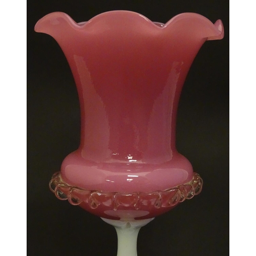 169 - A glass vase, the pink glass body with wavy rim and clear frilled decoration, raised over a milk gla... 