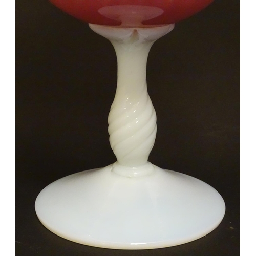 169 - A glass vase, the pink glass body with wavy rim and clear frilled decoration, raised over a milk gla... 