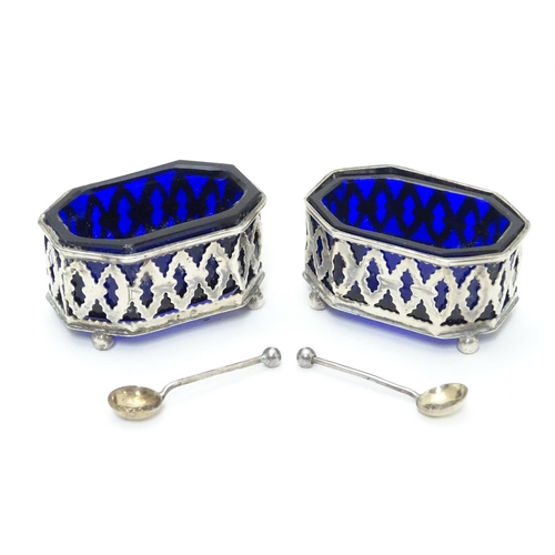 228 - A pair of silver salts with pierced decoration and blue glass liners, raised on four ball feet. Toge... 