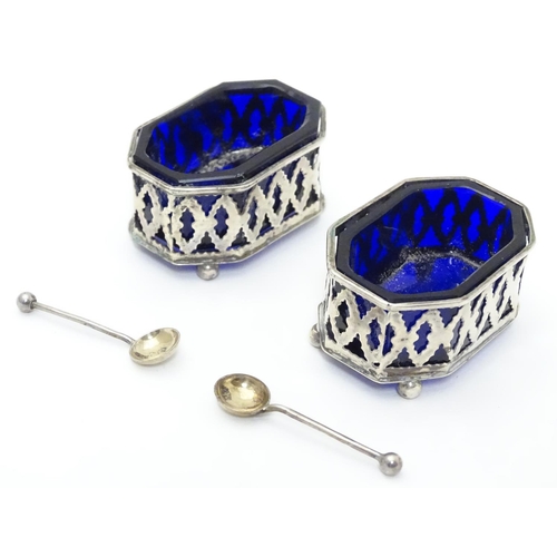 228 - A pair of silver salts with pierced decoration and blue glass liners, raised on four ball feet. Toge... 