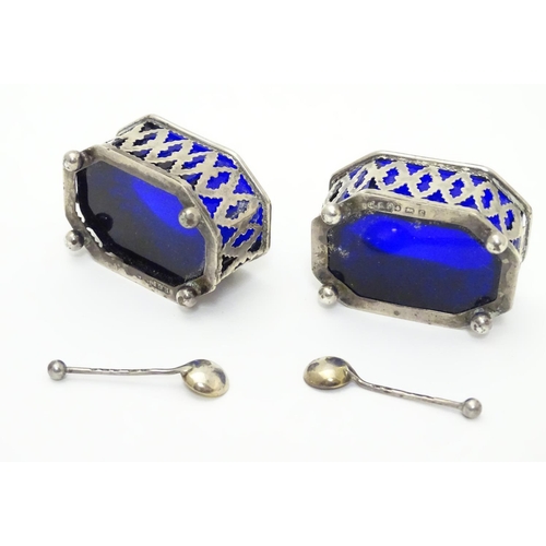 228 - A pair of silver salts with pierced decoration and blue glass liners, raised on four ball feet. Toge... 