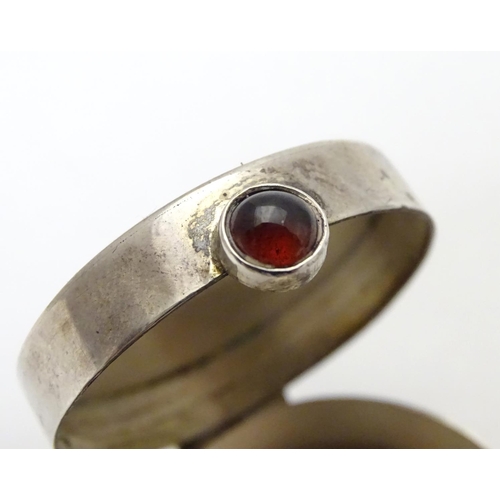 270 - A circular silver pill box with garnet coloured cabochon opener. Bears import hallmarks for Sheffiel... 