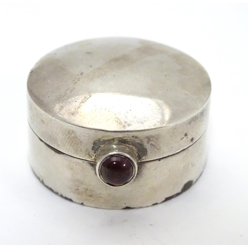 270 - A circular silver pill box with garnet coloured cabochon opener. Bears import hallmarks for Sheffiel... 