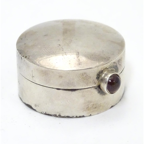 270 - A circular silver pill box with garnet coloured cabochon opener. Bears import hallmarks for Sheffiel... 