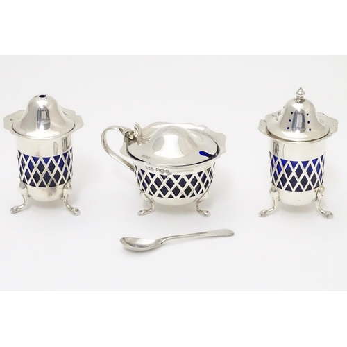 278 - A silver three piece cruet set with pierced lattice decoration. With blue glass liners and associate... 