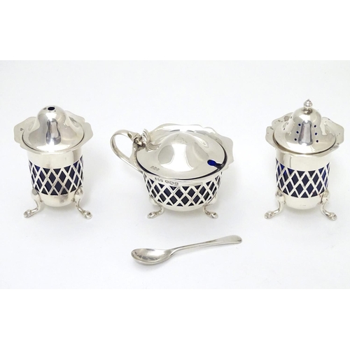 278 - A silver three piece cruet set with pierced lattice decoration. With blue glass liners and associate... 