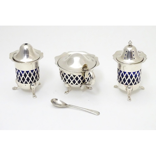 278 - A silver three piece cruet set with pierced lattice decoration. With blue glass liners and associate... 