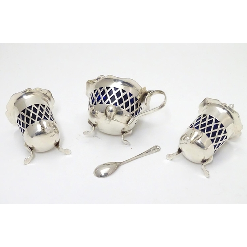 278 - A silver three piece cruet set with pierced lattice decoration. With blue glass liners and associate... 