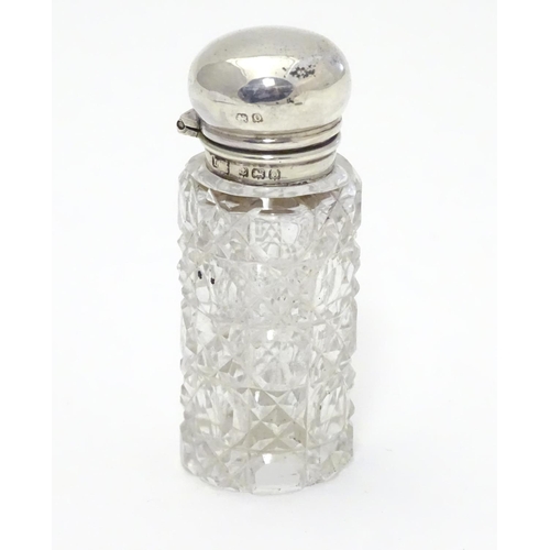 346 - A cut glass scent / perfume bottle with silver mount and lid, hallmarked  Birmingham 1913. 2 1/2