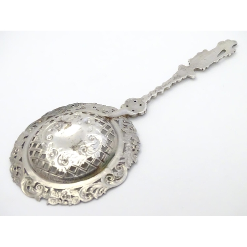 348 - An ornate silver strainer / sifter spoon with figural detail to handle and floral and acanthus detai... 