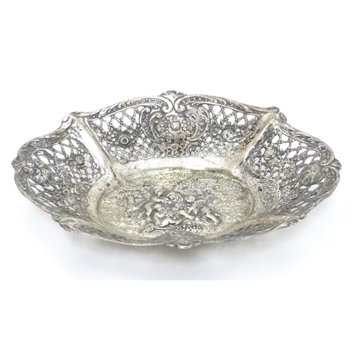 356 - A Continental silver dish of basket form with lattice decoration and cast cherub scene. 7 1/4