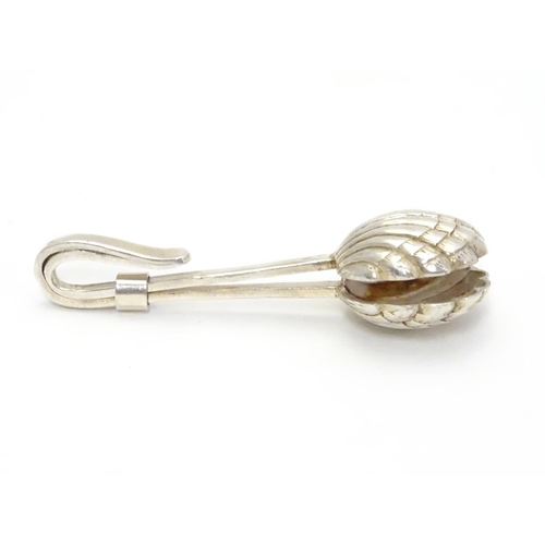 389 - A white metal napkin clip with scallop shell formed grips. 2