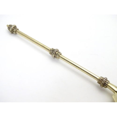 406 - An unusual silver gilt serving spoon, the bowl having rounded serrated edge, the stem and terminal h... 