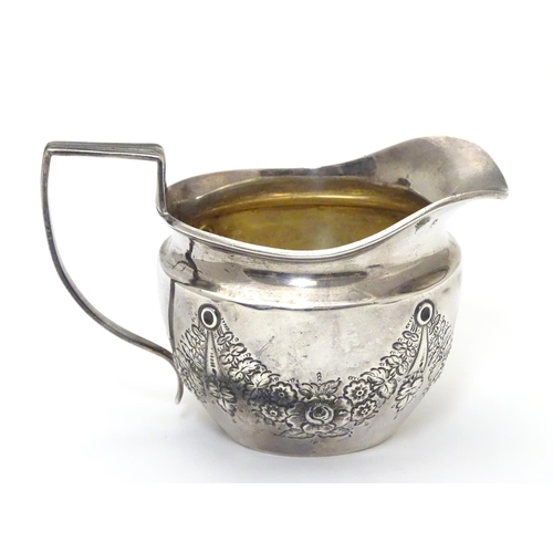 409 - A silver cream jug decorated with floral swags and with part gilded interior. Hallmarked Birmingham ... 