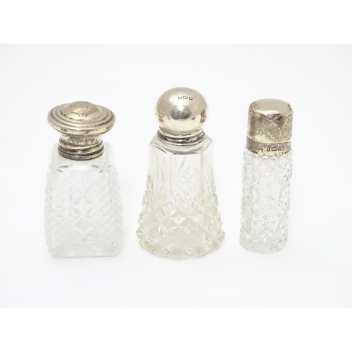 415A - 3 various cut glass perfume / scent bottles with silver tops. The tallest 3 1/2