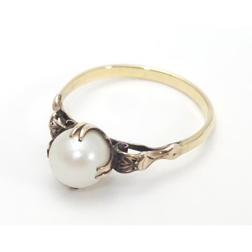 441 - A yellow metal ring with claw set pearl and decorative shoulders. Ring size approx O