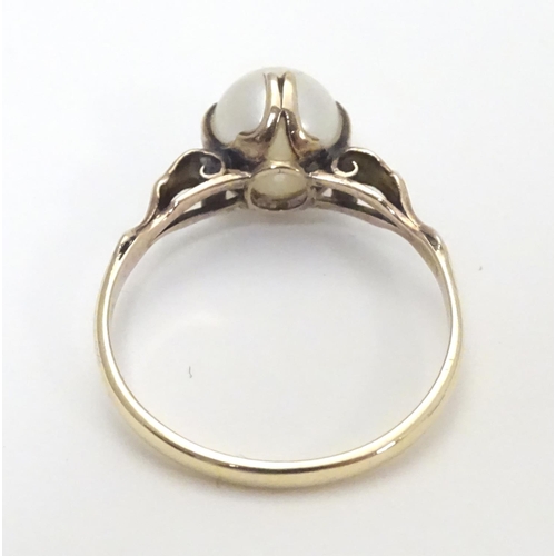 441 - A yellow metal ring with claw set pearl and decorative shoulders. Ring size approx O