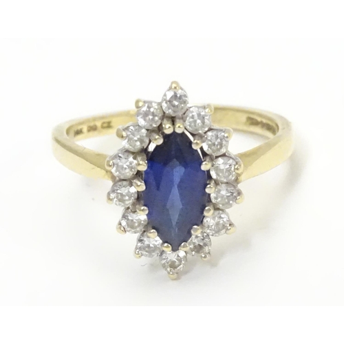 443 - A 14k gold ring set with central sapphire bordered by white stones. Ring size approx N 1/2