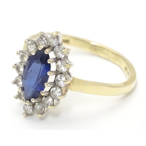 443 - A 14k gold ring set with central sapphire bordered by white stones. Ring size approx N 1/2