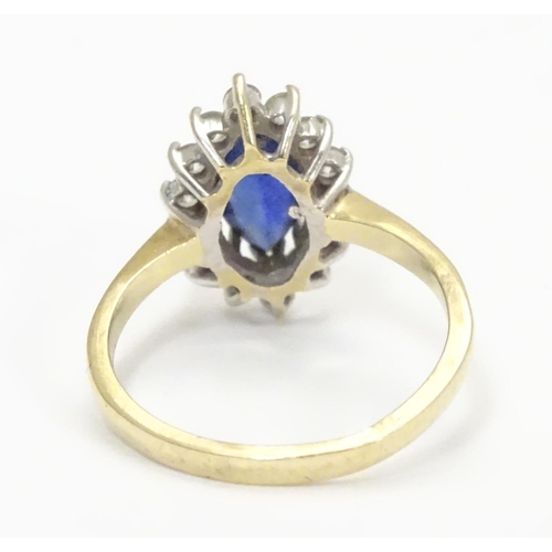 443 - A 14k gold ring set with central sapphire bordered by white stones. Ring size approx N 1/2