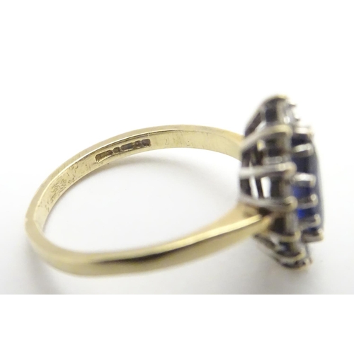 443 - A 14k gold ring set with central sapphire bordered by white stones. Ring size approx N 1/2