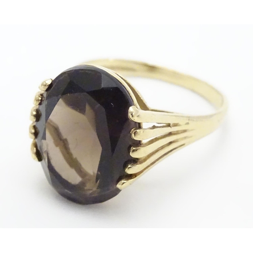 445 - A 9ct gold ring set with central oval smoky quartz in a claw setting. Ring size approx M