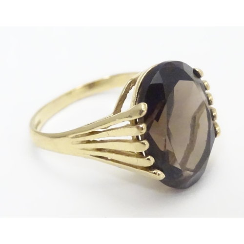 445 - A 9ct gold ring set with central oval smoky quartz in a claw setting. Ring size approx M