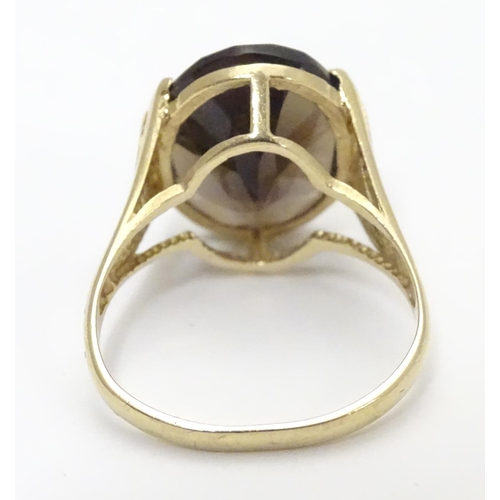 445 - A 9ct gold ring set with central oval smoky quartz in a claw setting. Ring size approx M