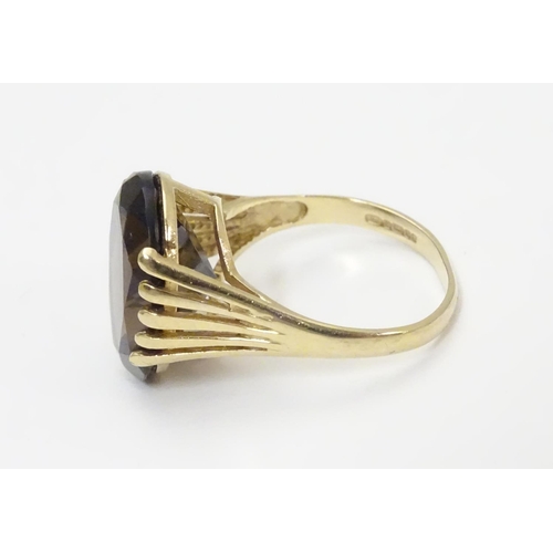 445 - A 9ct gold ring set with central oval smoky quartz in a claw setting. Ring size approx M