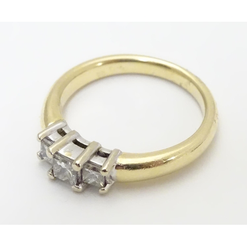 446 - A 14kt gold ring set with trio of diamonds. The central diamond approx. 1/8