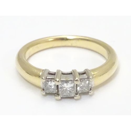 446 - A 14kt gold ring set with trio of diamonds. The central diamond approx. 1/8