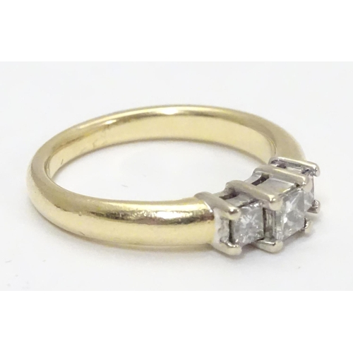 446 - A 14kt gold ring set with trio of diamonds. The central diamond approx. 1/8