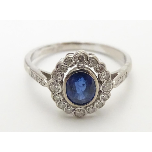 450 - An 18ct white gold ring set with central sapphire bordered by diamonds