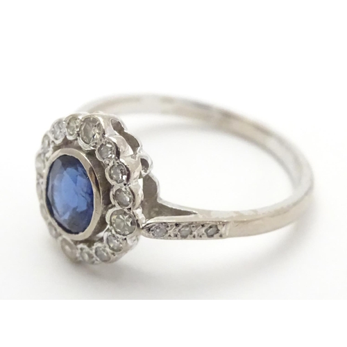 450 - An 18ct white gold ring set with central sapphire bordered by diamonds