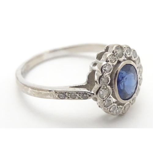 450 - An 18ct white gold ring set with central sapphire bordered by diamonds