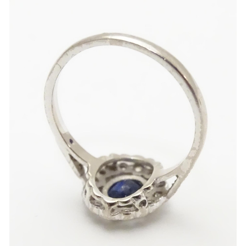 450 - An 18ct white gold ring set with central sapphire bordered by diamonds