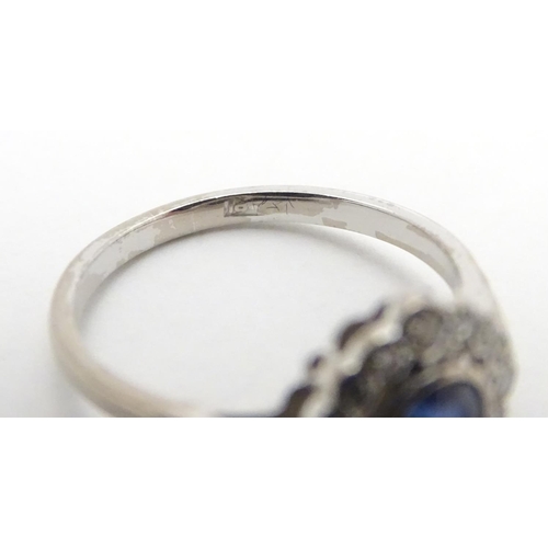 450 - An 18ct white gold ring set with central sapphire bordered by diamonds